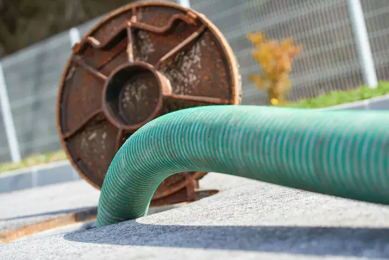 Green suction hose connected to an open septic tank riser during pumping