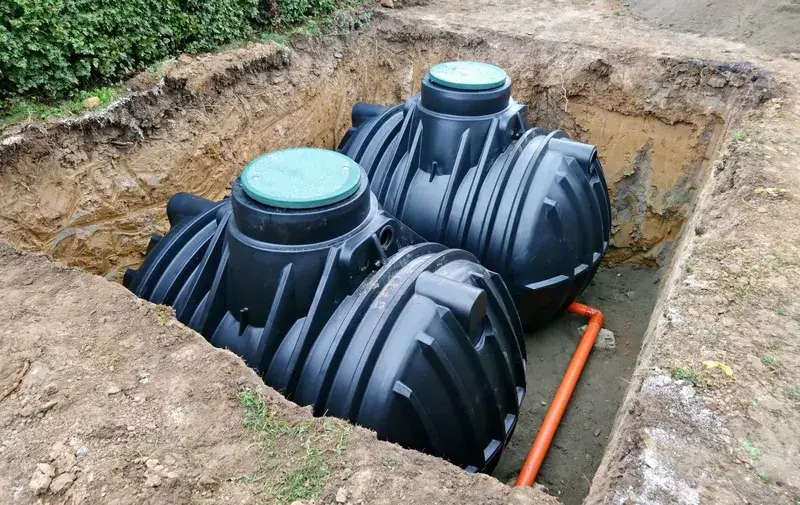 Two black plastic septic tanks set into an open excavation
