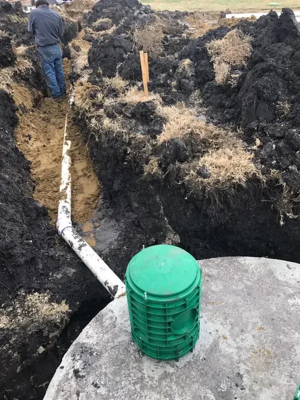 New septic line trench with a green riser lid in the foreground