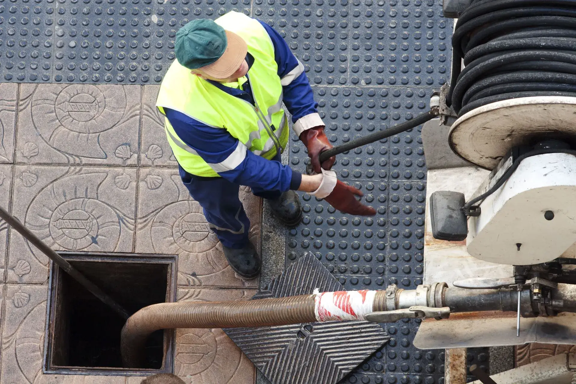 Technician in high-visibility gear servicing a tank from a vacuum truck
