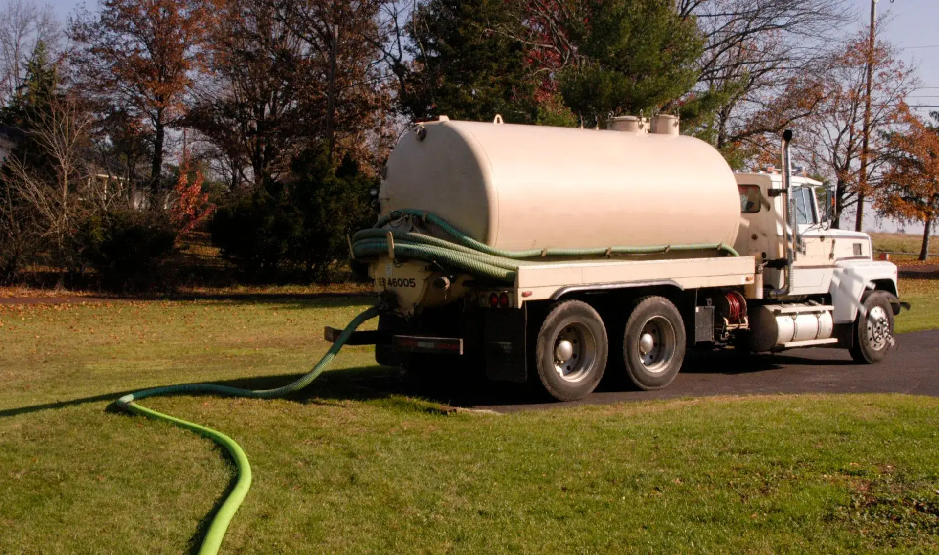 Septic pump truck with hose deployed on a residential lawn